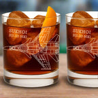 Two glasses of a drink with ice cubes and an orange slice, featuring the Sukhoi SU-30 MKI design.