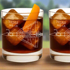 Two glasses of dark liquid with ice cubes and an orange slice, featuring 'TEJAS MK-IA' design.