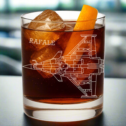 Glass with a design of an aircraft labeled 'RAFALE' and ice cubes, on a blurred background.