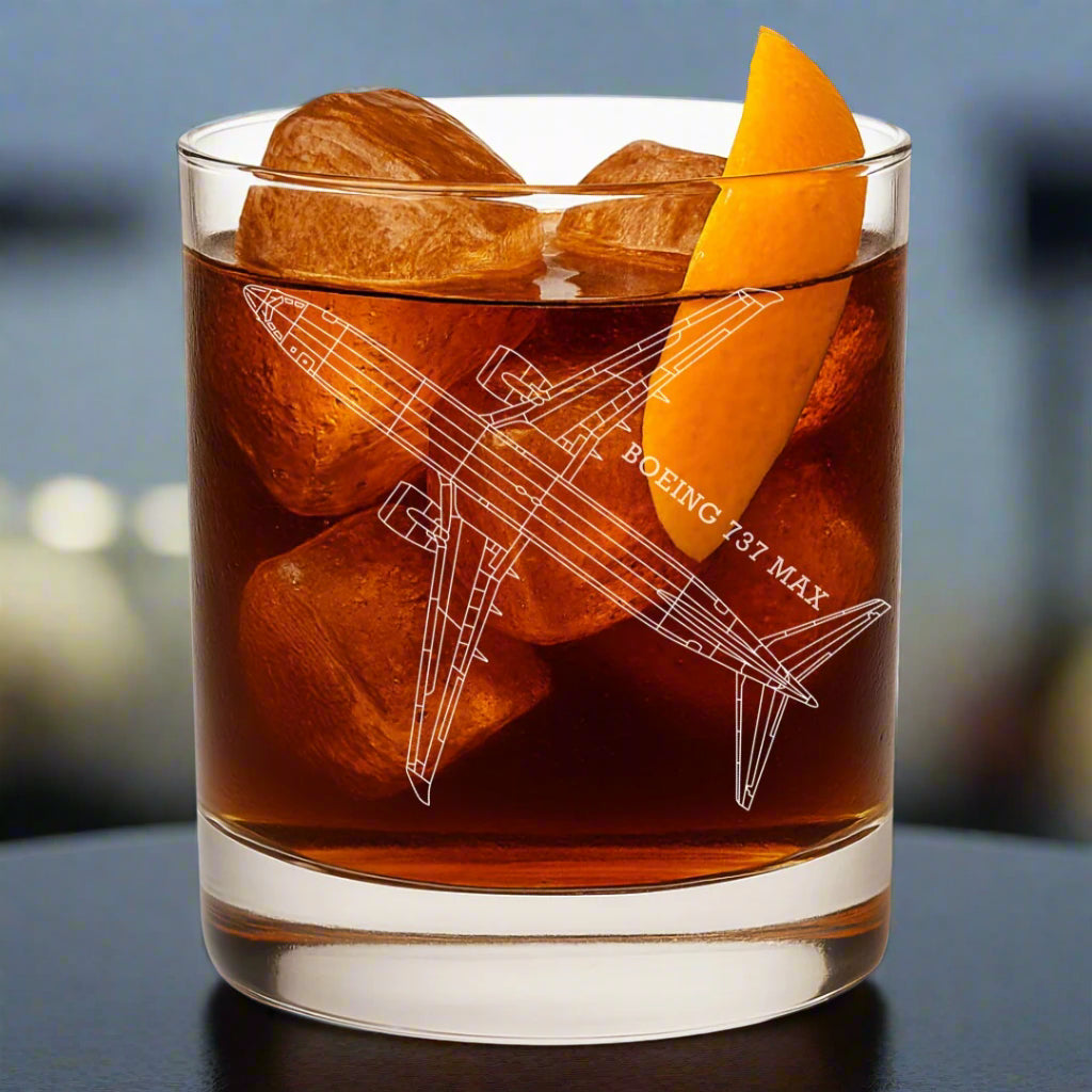 Glass of brown liquid with ice cubes and an orange slice, featuring a Boeing 737 MAX aircraft illustration.