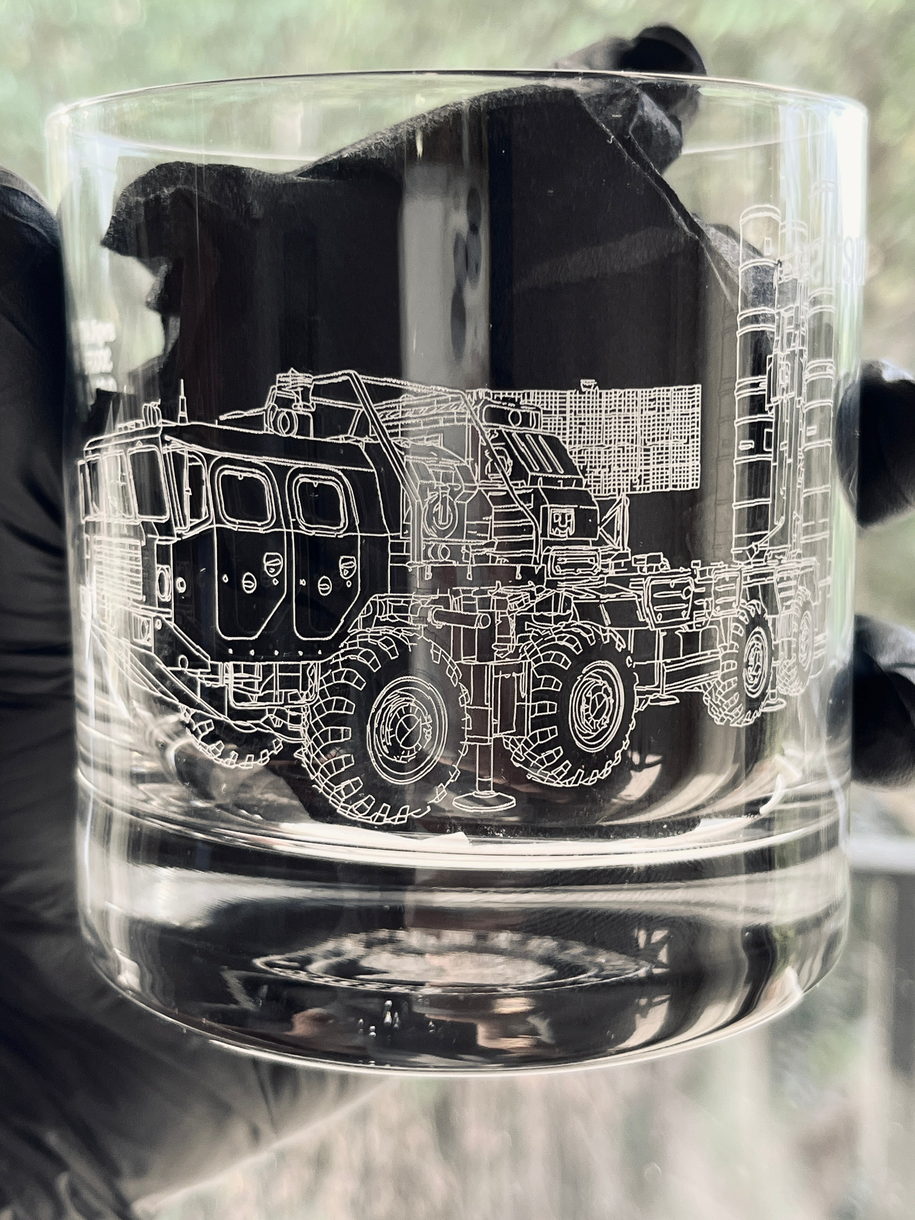 Clear glass tumbler with a detailed black and white illustration of a s400 launcher on a blurred background