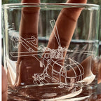Clear glass tumbler with a chetak helicopter engraving held by hands