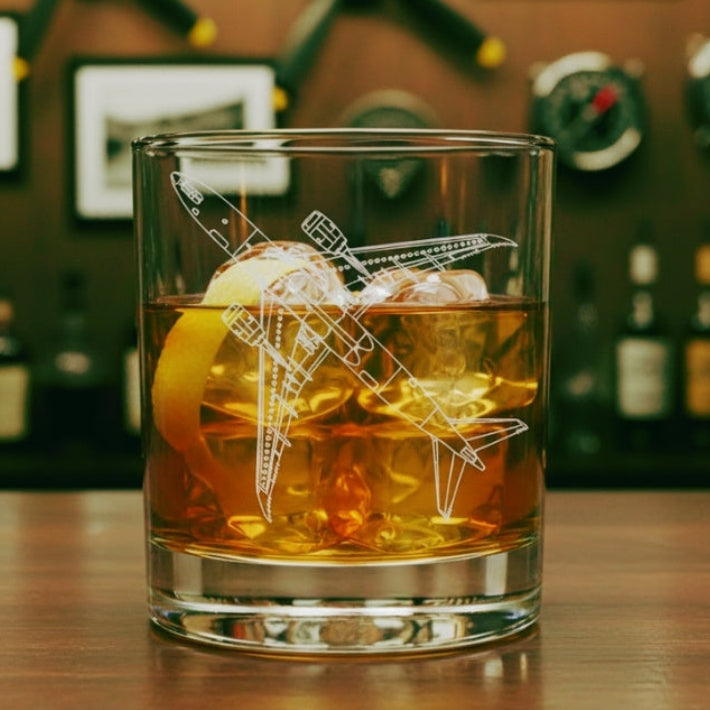 Glass of whiskey with ice cubes and a 787 dreamliner airplane design on a bar counter.