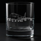 A clear glass rocks tumbler with an etched outline of a boeing 747 passenger airplane on the front, shown against a solid black background.