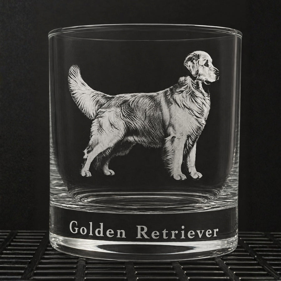 A clear glass rocks tumbler featuring an engraved profile illustration of a Golden Retriever and the text 'Golden Retriever' printed on the base, set against a dark background.