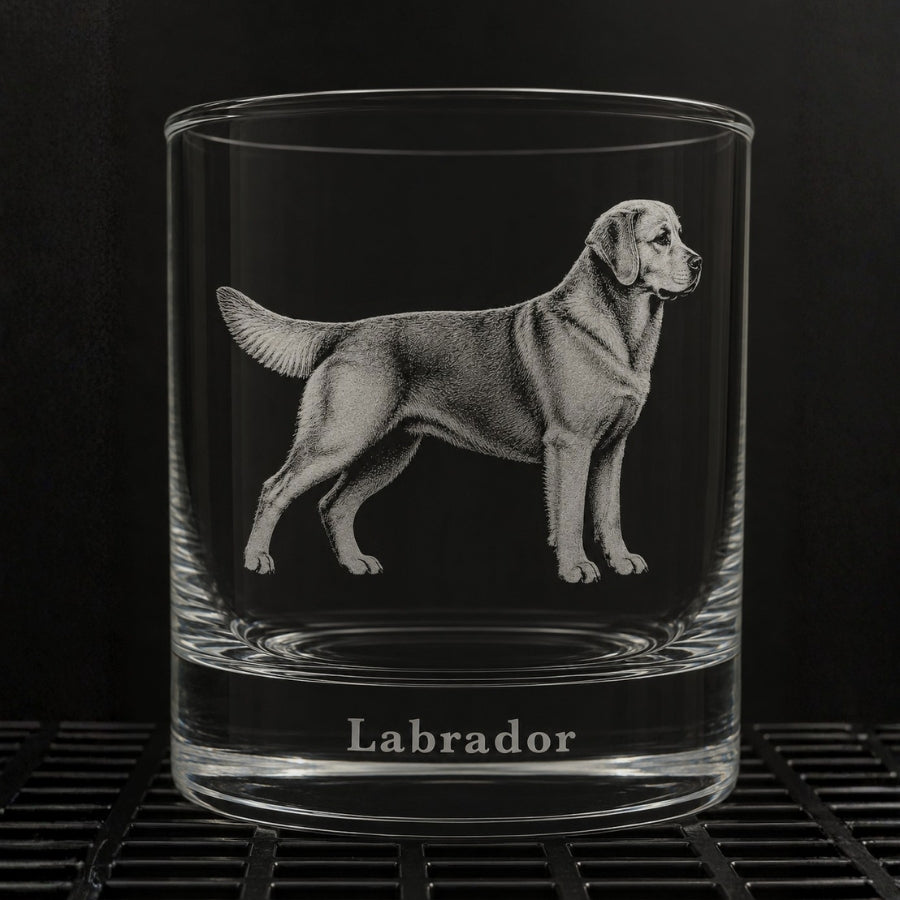 A clear glass rocks tumbler featuring an engraved Labrador dog illustration and the word 'Labrador' at the base, shown against a dark background.