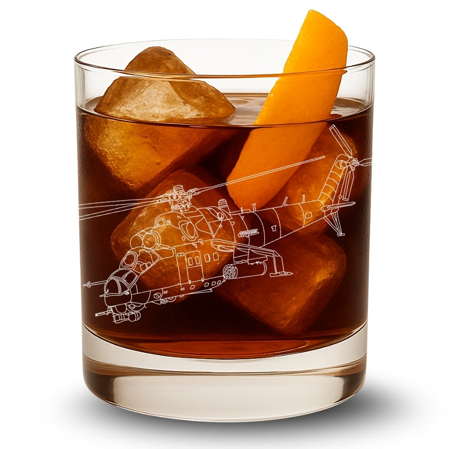 Glass of brown liquid with helicopter engraving design, ice cubes, and orange peel on a white background