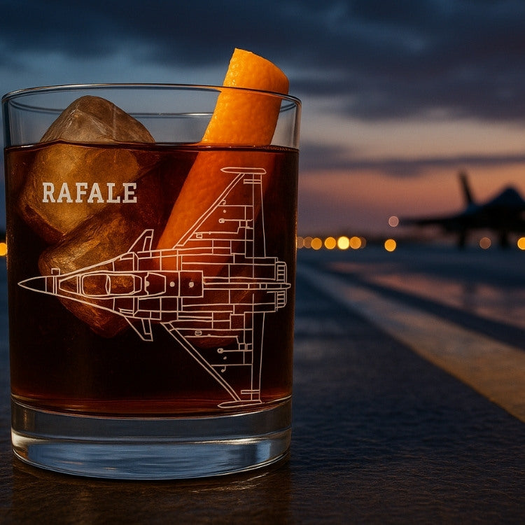 Glass of dark liquid with 'RAFALE' and fighter jet design, against a blurred runway background.