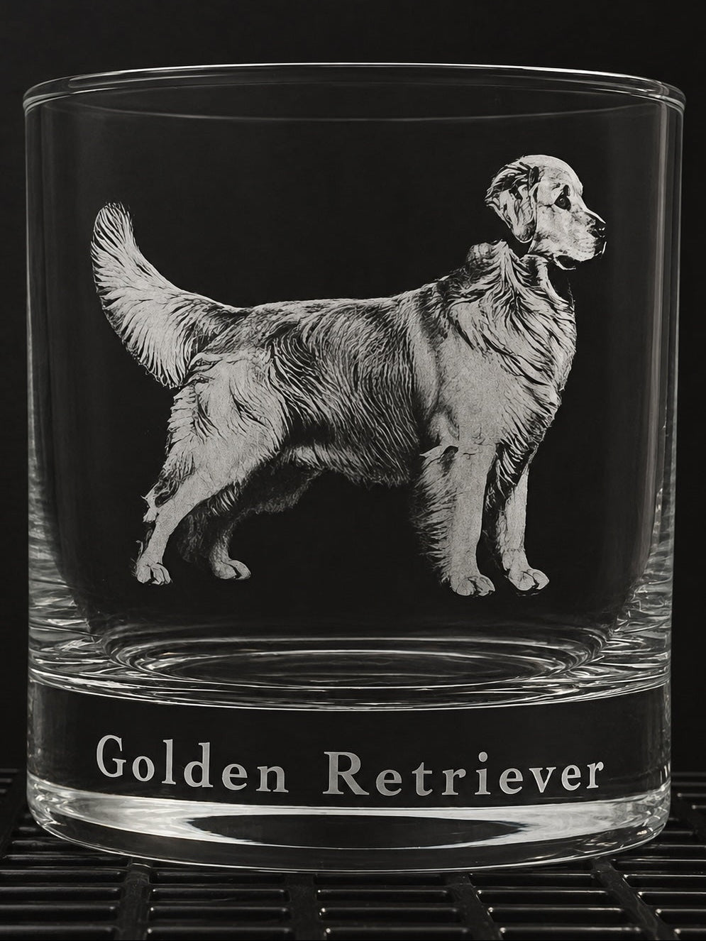 A clear glass rocks tumbler featuring an engraved profile illustration of a Golden Retriever and the text 'Golden Retriever' printed on the base, set against a dark background.