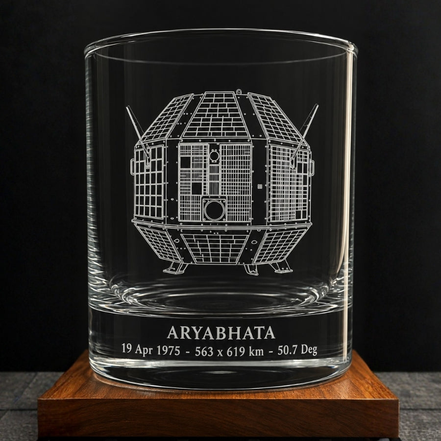 a line drawing of the indian aryabhata satellite engraved on a crystal whiskey glass with the name and facts like launch date, orbit distance and apogee written below the glass.