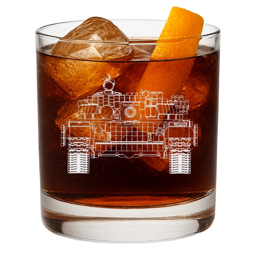 Glass of dark liquid with ice and an orange peel, featuring a t71 tank blueprint etching.